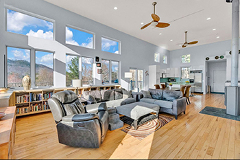 brightly lit living room with wall of windows behind a couch arrangement