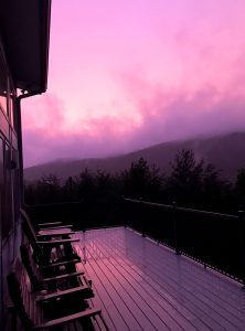 incredible purple and magenta mist rises up from the mountains and reflects in the rain-covered deck