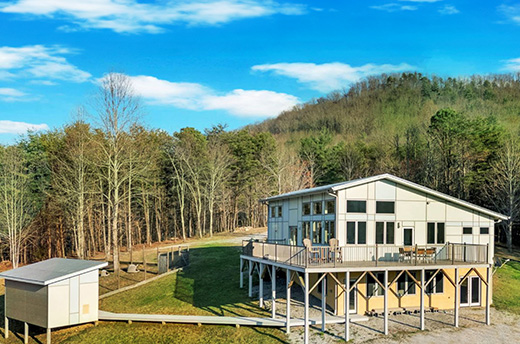 modern two level house with double slant roof, walls of windows and wraparound deck