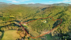 overhead drone photo of mountains and two houses has a red line overlayed to indicate property line