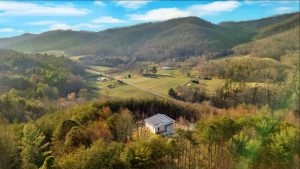 Overhead photograph of contemporary mountain house shows the solar panels on house roof as well as long range views of mountains and farmland