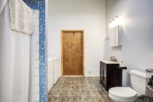 large, brightly lit full bath with tiled shower and washer and dryer