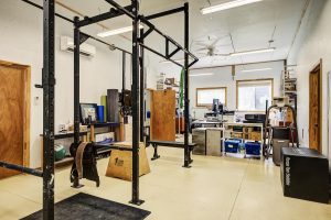 weight lifting cage and pull-up bar in the foreground, with an eliptical machine