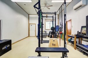 gym equipment, weight cage and jump boxes photographed inside a cavernous room with tall ceilings and large windows