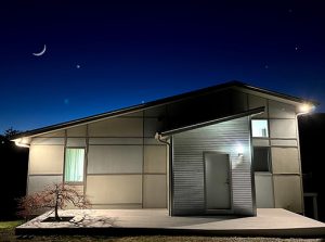 long-exposure photograph of front of contemporary house with indigo blue sky and crescent moon