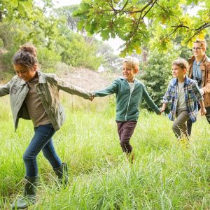 kids holding hands and trapsing through grass