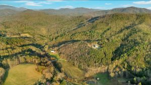 Very high overhead drone shot shows two houses surrounded by mountain ranges