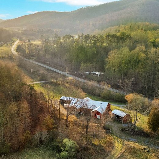 pastoral overhead photo of a valley between mountains and a sprawling complex of red barns
