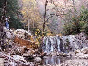 waterfalls in Paint Creek Recreation area and a fisherman standing on the a boulder on the side