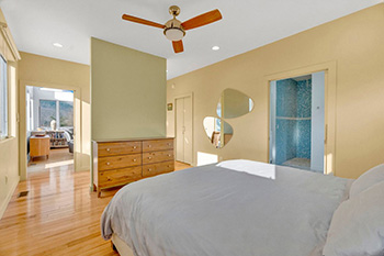 Main bedroom is flooded with sunlight that is reflecting off the sculptural wall mirror and provides a peek into the ensuite rainshower