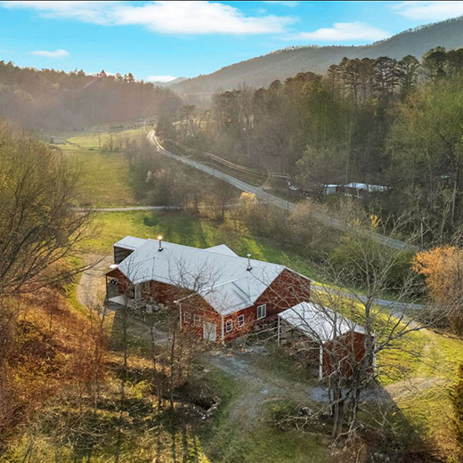 red barn with white roof stands in a valley between two mountain ranges