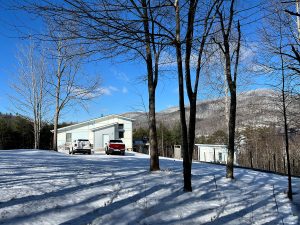 crisp winter day on a snowy mountaintop modern house on ridge with two cars in front