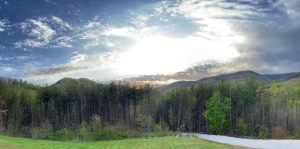 wide angle mountain view with sun setting in a cloud-filled sky
